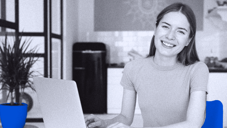 foto-em-preto-e-branco-com-detalhes-azuis-de-mulher-sorrindo-diante-de-sua-mesa-de-trabalho