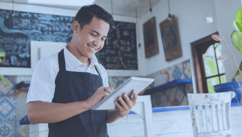 foto-de-homem-com-tablet-na-mao-diante-de-seu-restaurante-recem-comprado-representando-o-ato-de-comprar-um-restaurante